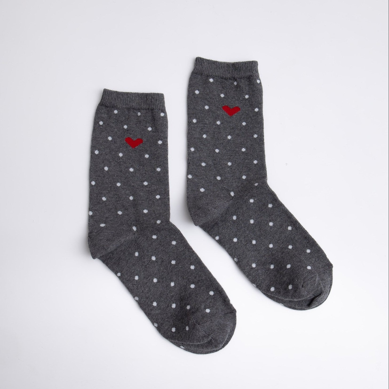 Pair of gray socks with white polka dots and red hearts on a light gray background

