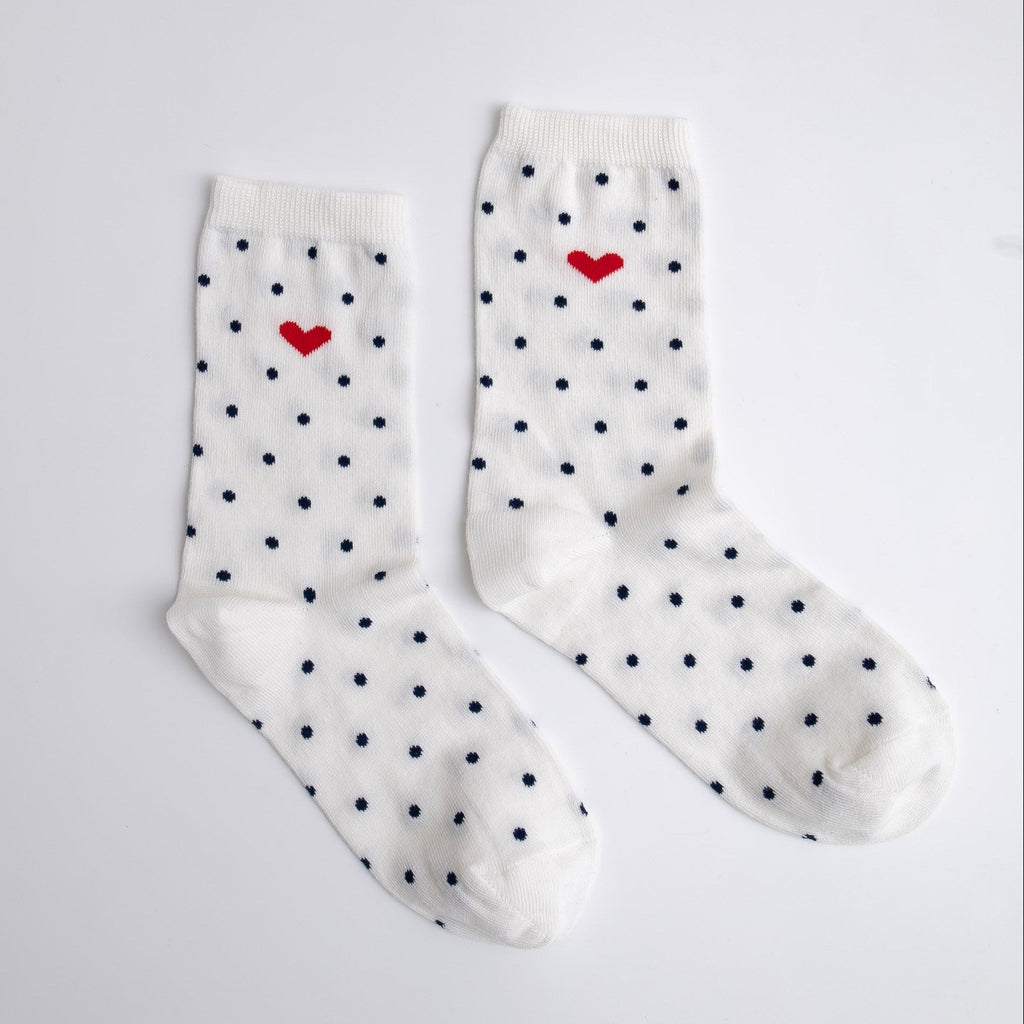 White socks with black polka dots and red hearts on a light gray background
