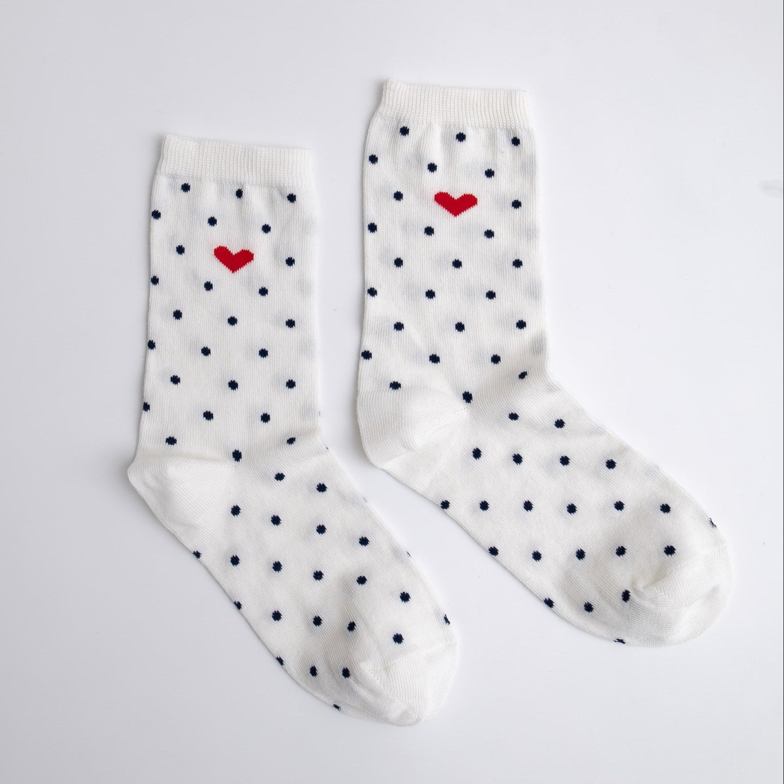 White socks with black polka dots and red hearts on a light gray background
