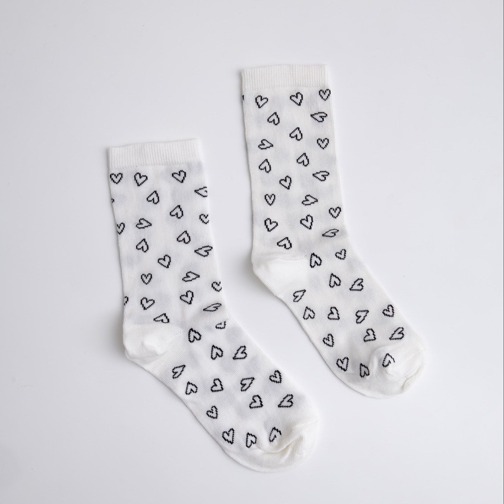 White socks with black heart pattern on a light gray background

