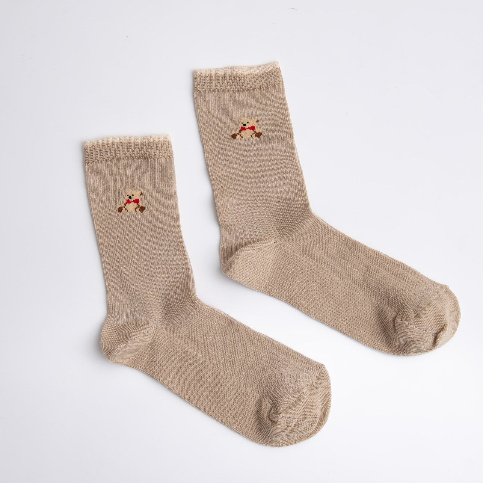 Pair of beige socks with small embroidered designs on a white background

