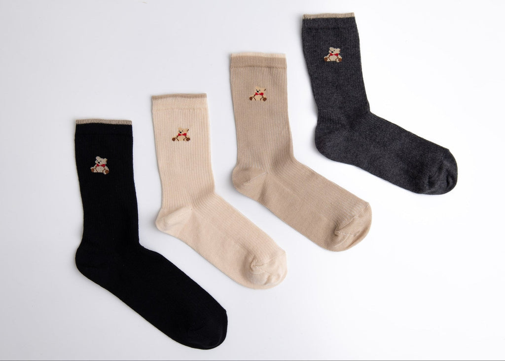 Four pairs of socks in black, beige, and gray on a white background

