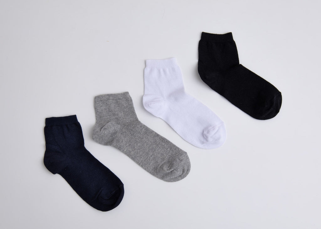 Four pairs of socks in black, gray, and white on a light gray background

