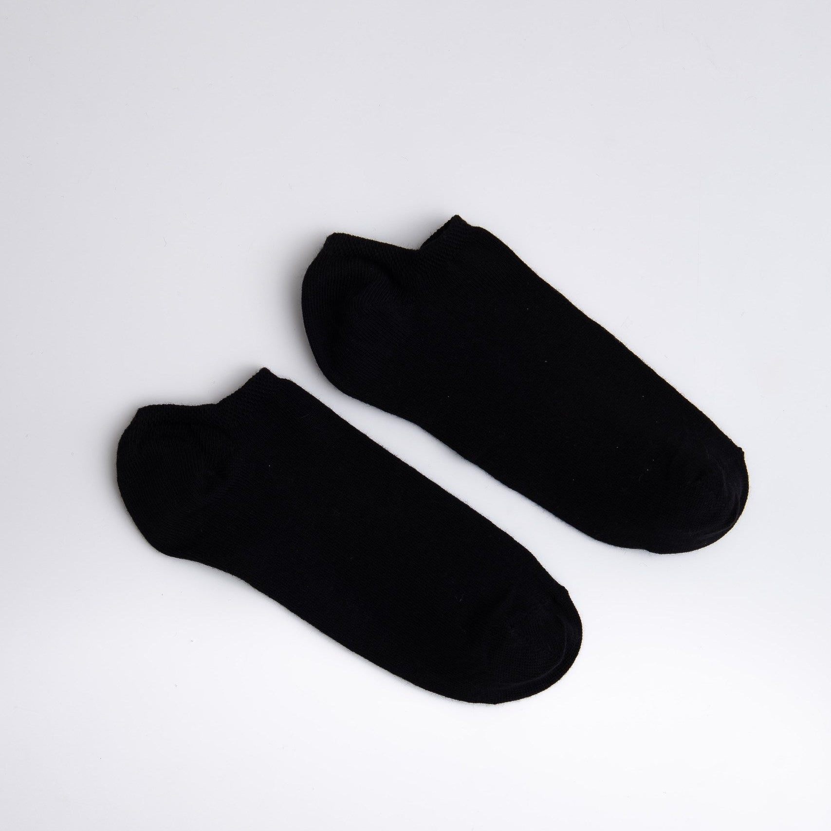 Two black ankle socks on a light gray background

