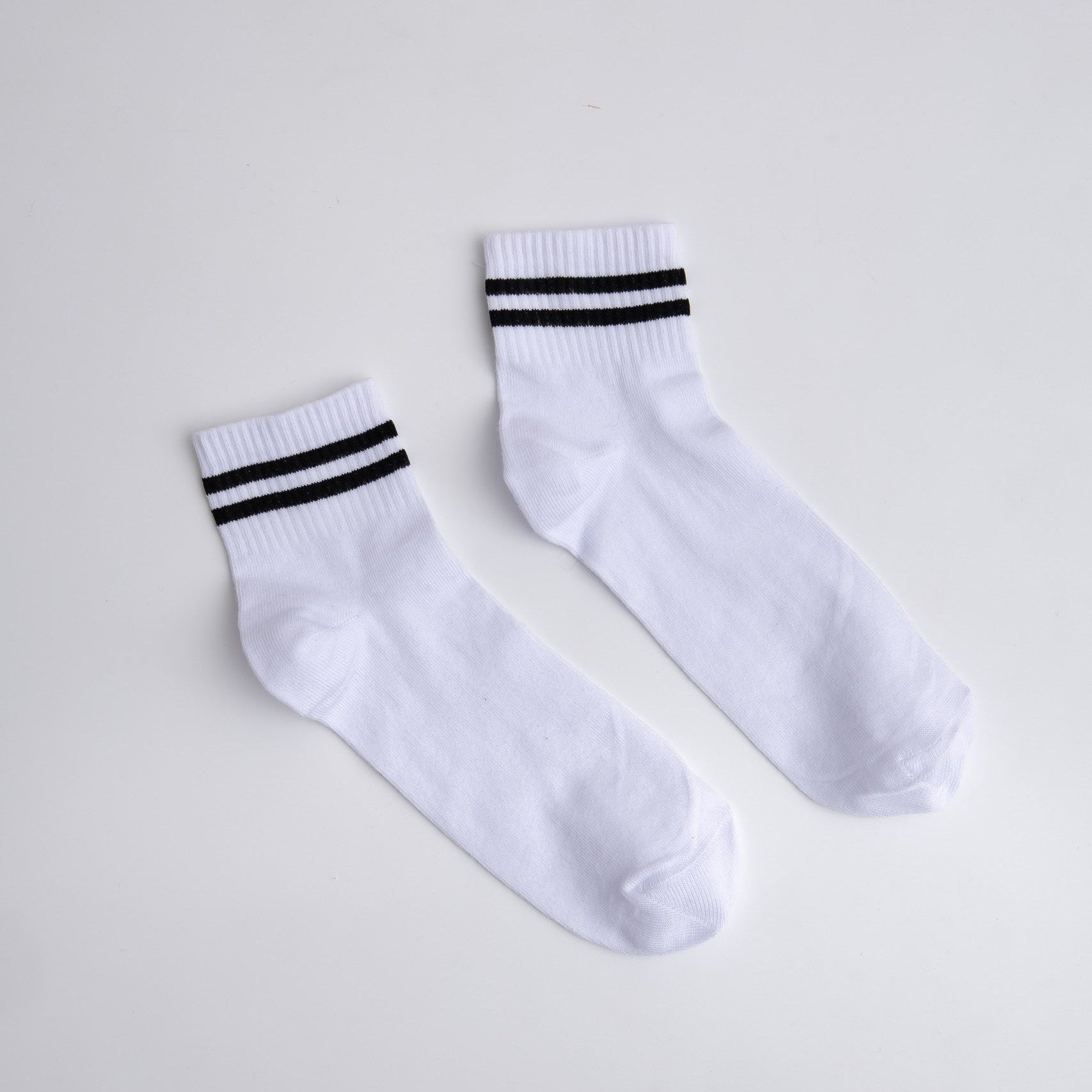 Pair of white socks with black stripes on a light gray background

