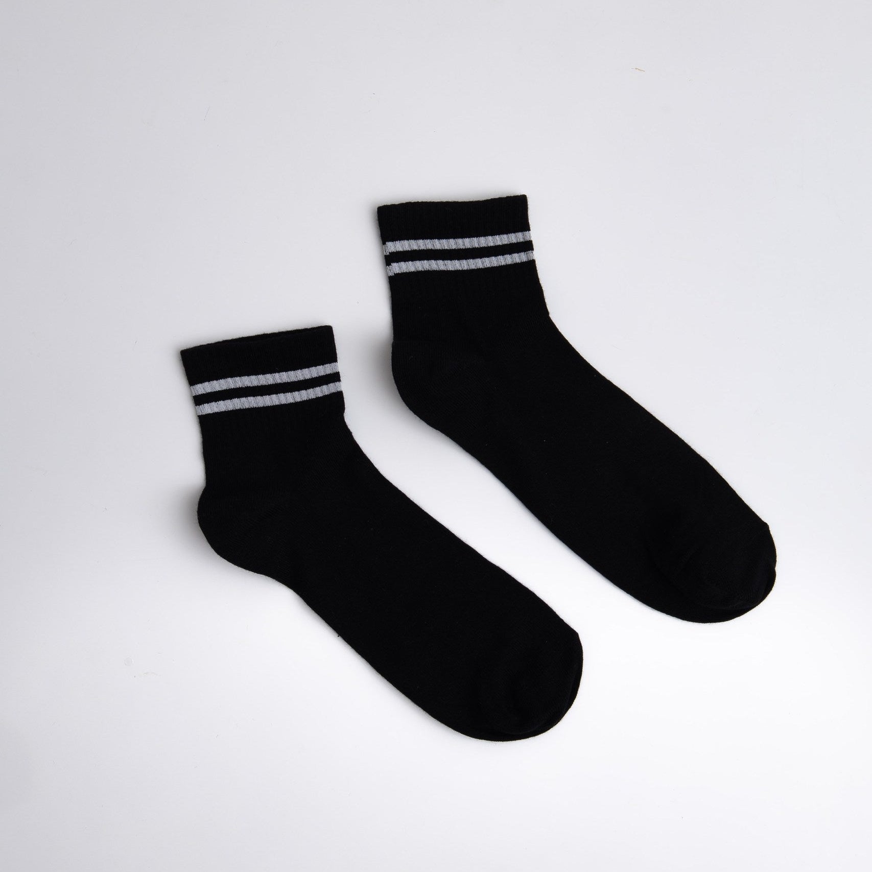 Pair of black socks with white stripes on a light gray background

