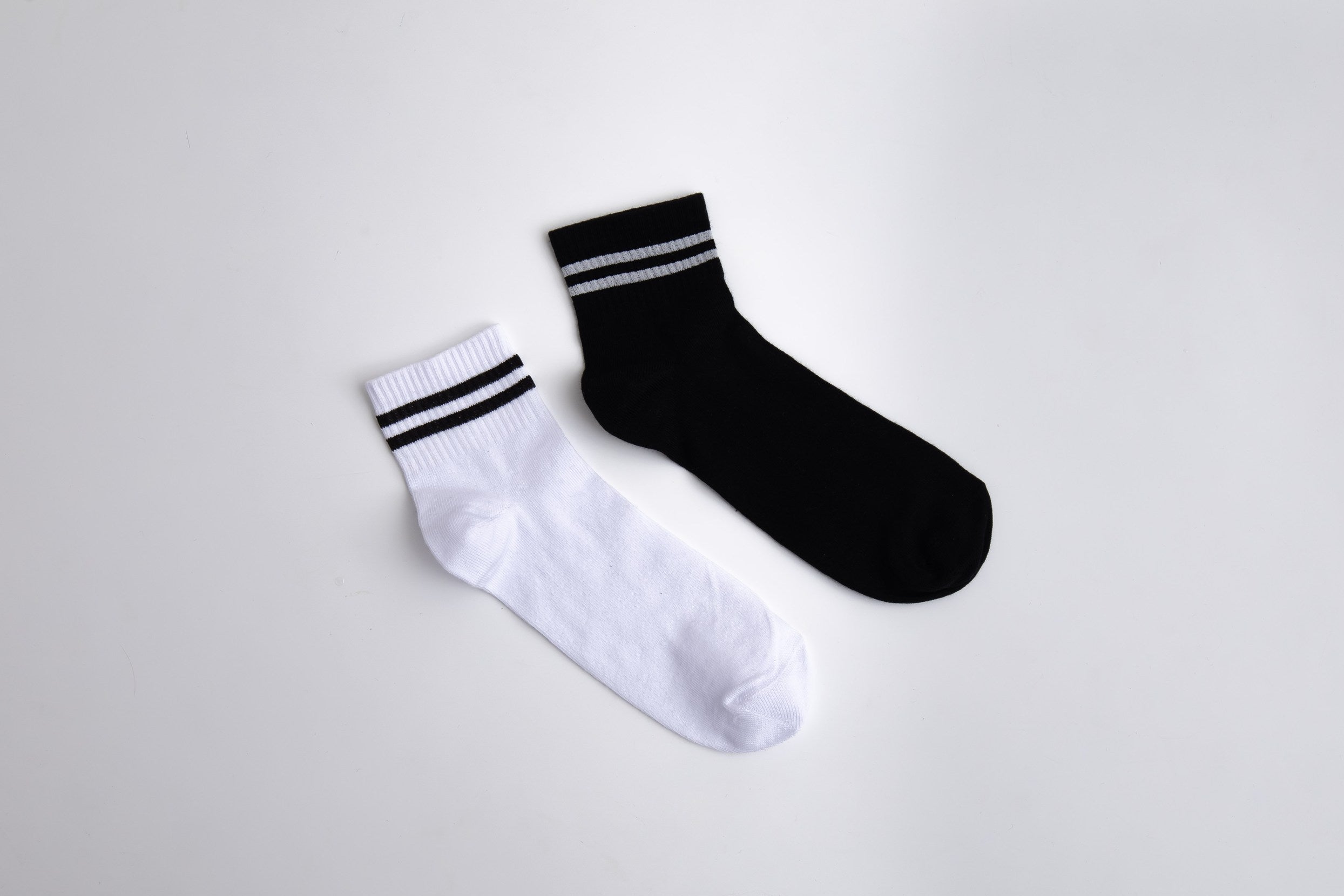 Two socks, one white and one black, with stripes on a light gray background

