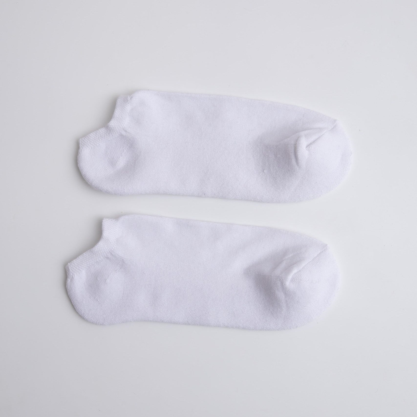 Two white ankle socks on a light gray background

