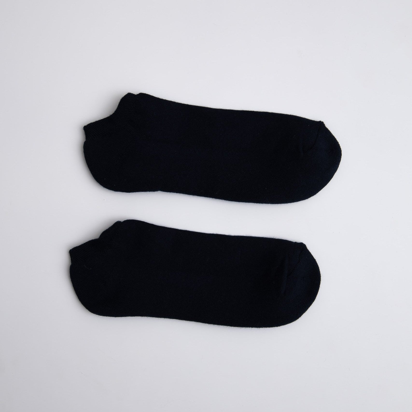 Two black ankle socks on a light gray background

