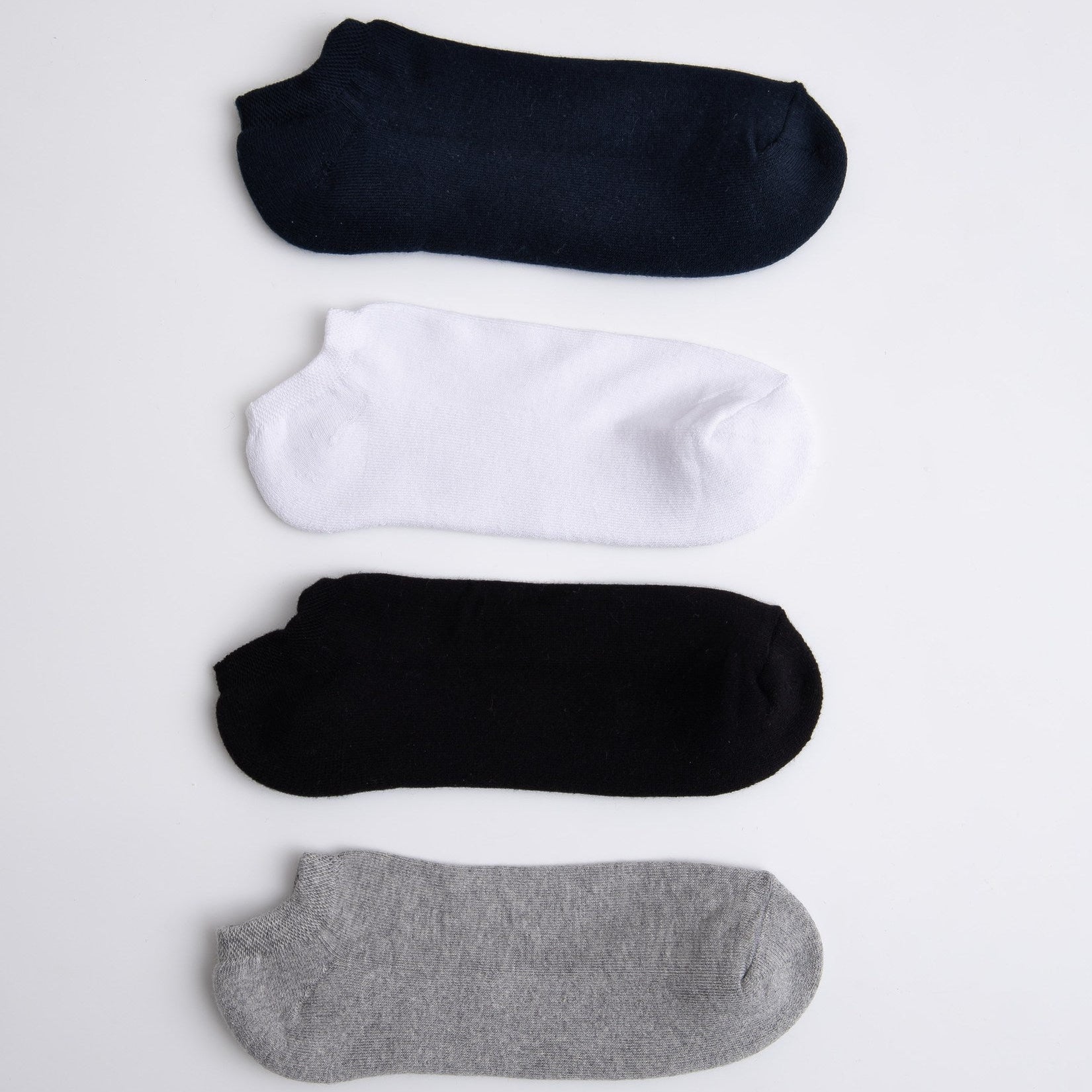 Four pairs of socks in black, white, and gray on a light gray background

