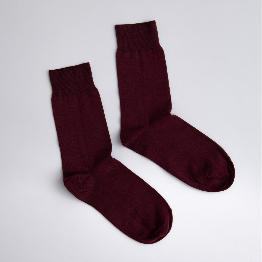 Pair of maroon socks on a light gray background

