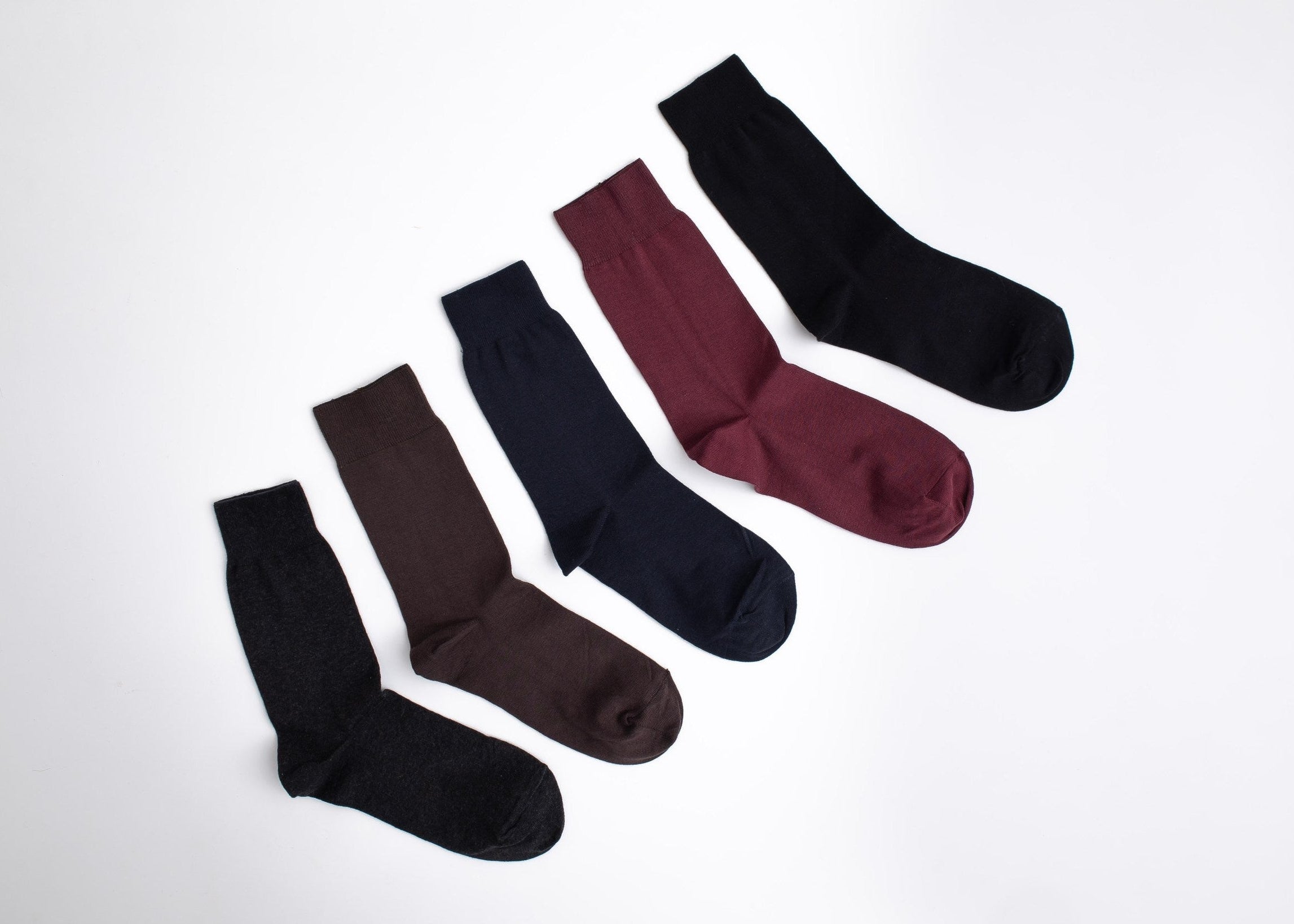 Set of five pairs of socks in black, brown, and burgundy on a white background

