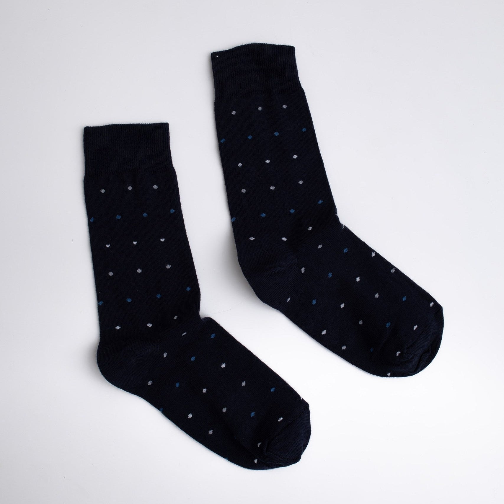Pair of black socks with white polka dots on a light gray background

