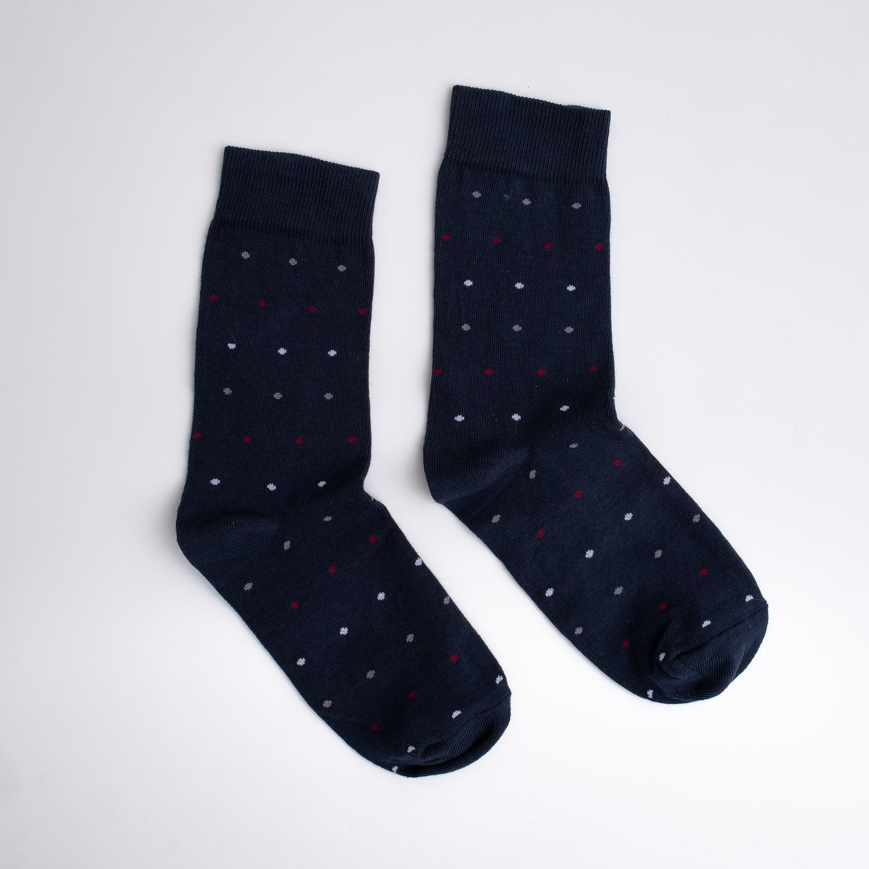 Pair of navy blue socks with white polka dots on a light gray background

