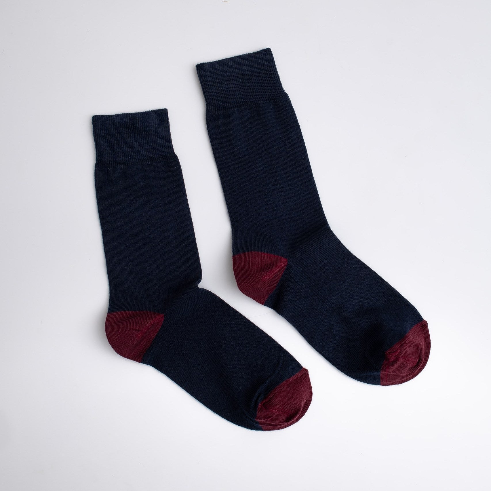 Pair of black socks with red toes and cuffs on a white background

